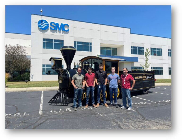 SMC engineers standing in front of Purdue University's Boilermaker Special VII and SMC building