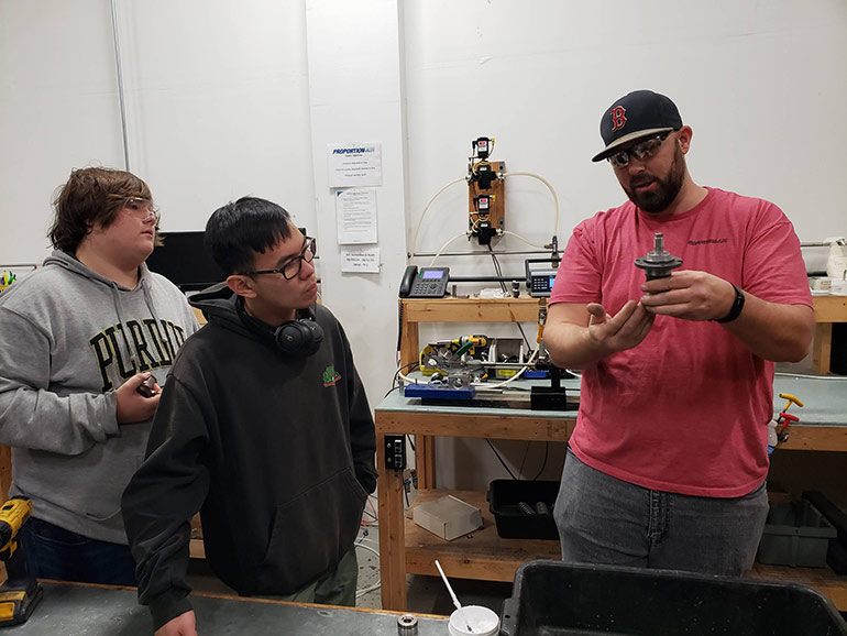 Cutline Purdue Team 15 Jeremy Capstone 2023: Burling Valve Production Manager Jeremy Carpenter (right) explains an internal part of a Burling regulator to Purdue Polytechnic Institute Team 15 members Hunter Kepner (left) and Ray Kurniawan (center). The team is working on improving the superheated steam capabilities of a Burling regulator.