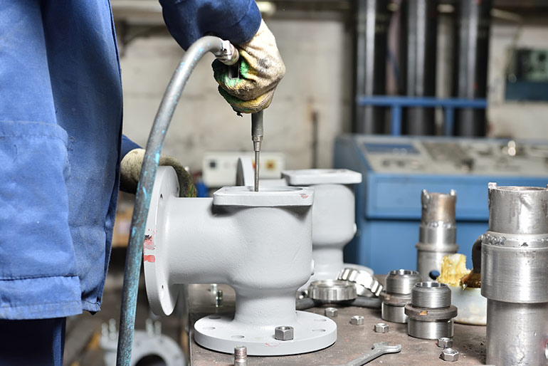 A worker uses high air pressure to blow away small debris before assembly. Image courtesy Shutterstock